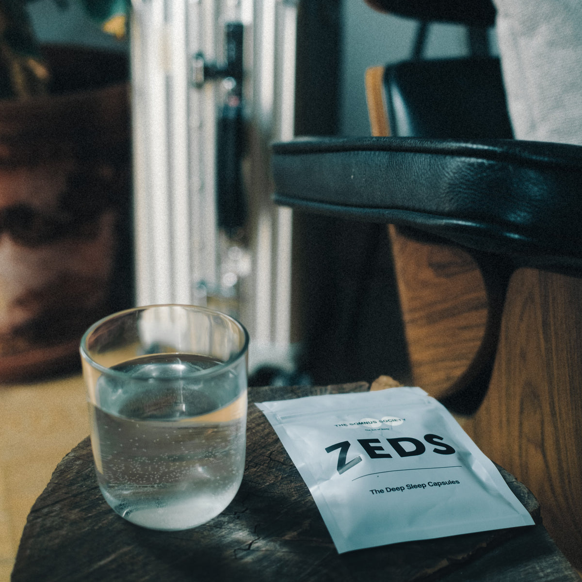A ZEDS pack and a glass of water resting on a dark wooden stool