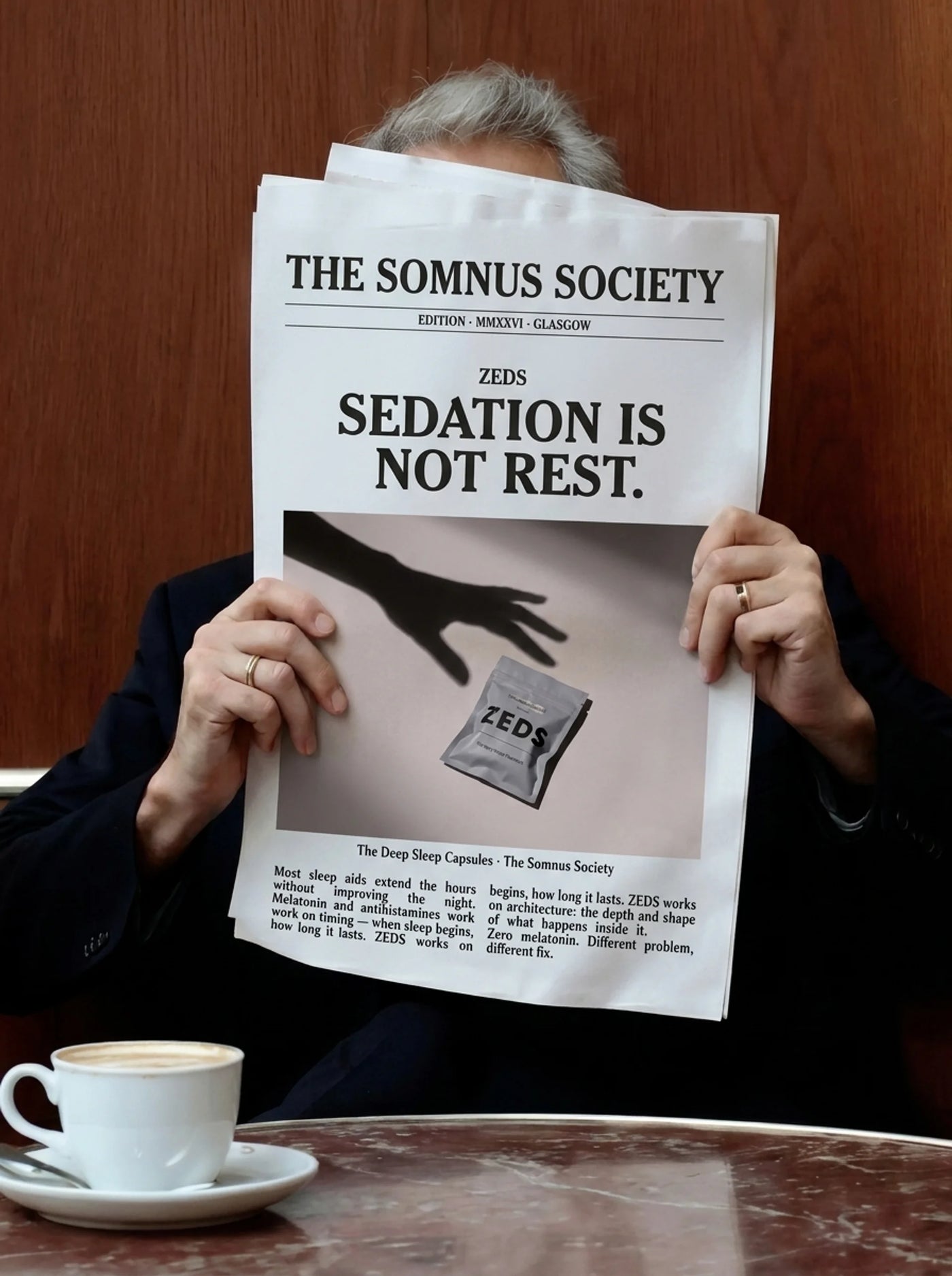A person holding The Somnus Society broadsheet, front page reading: Sedation is not rest.